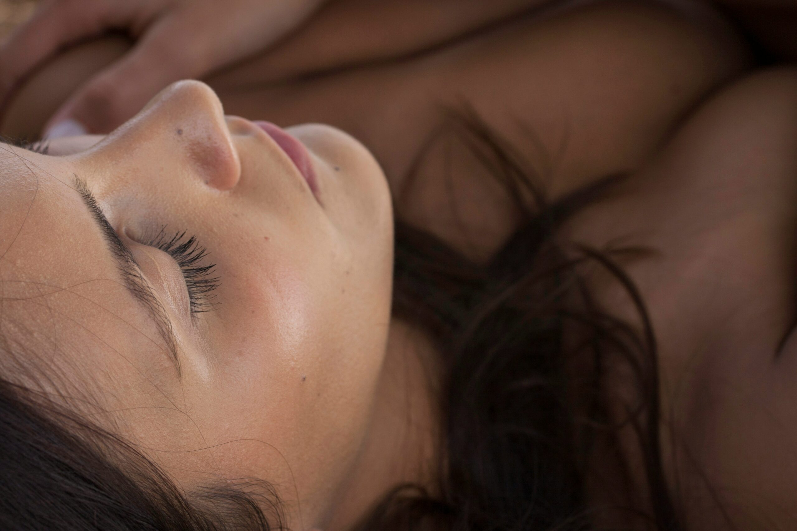 A woman peacefully sleeping with glowing skin under soft morning light representing beauty sleep and healthy skin.