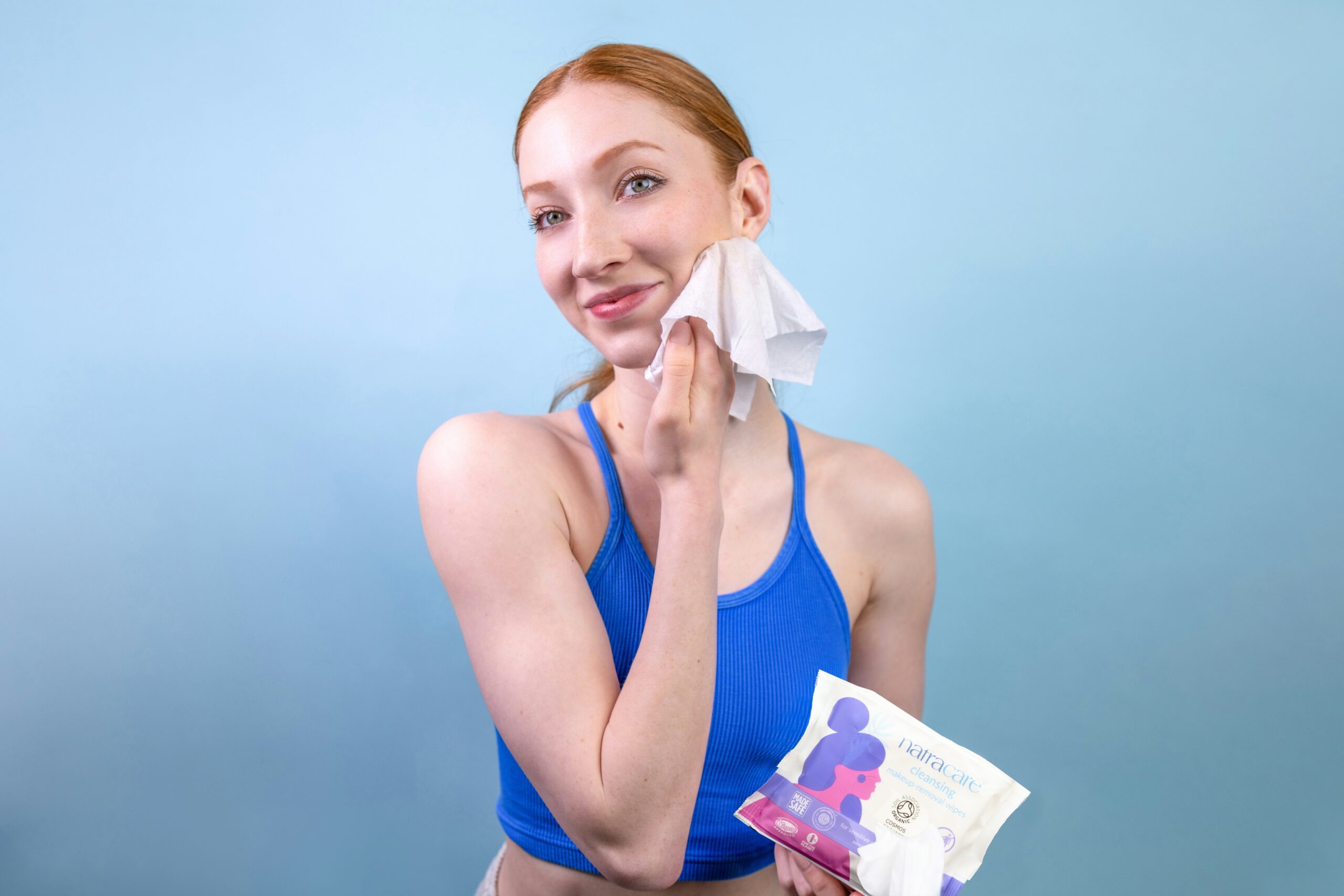 Woman in gym suit cleaning her face with wipes after workout, practicing post-workout skincare to prevent acne and refresh her skin.