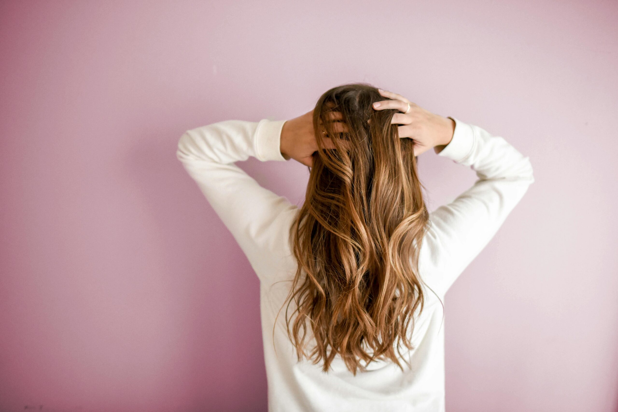 A woman massaging her scalp with her fingertips to promote scalp fitness and natural hair growth.