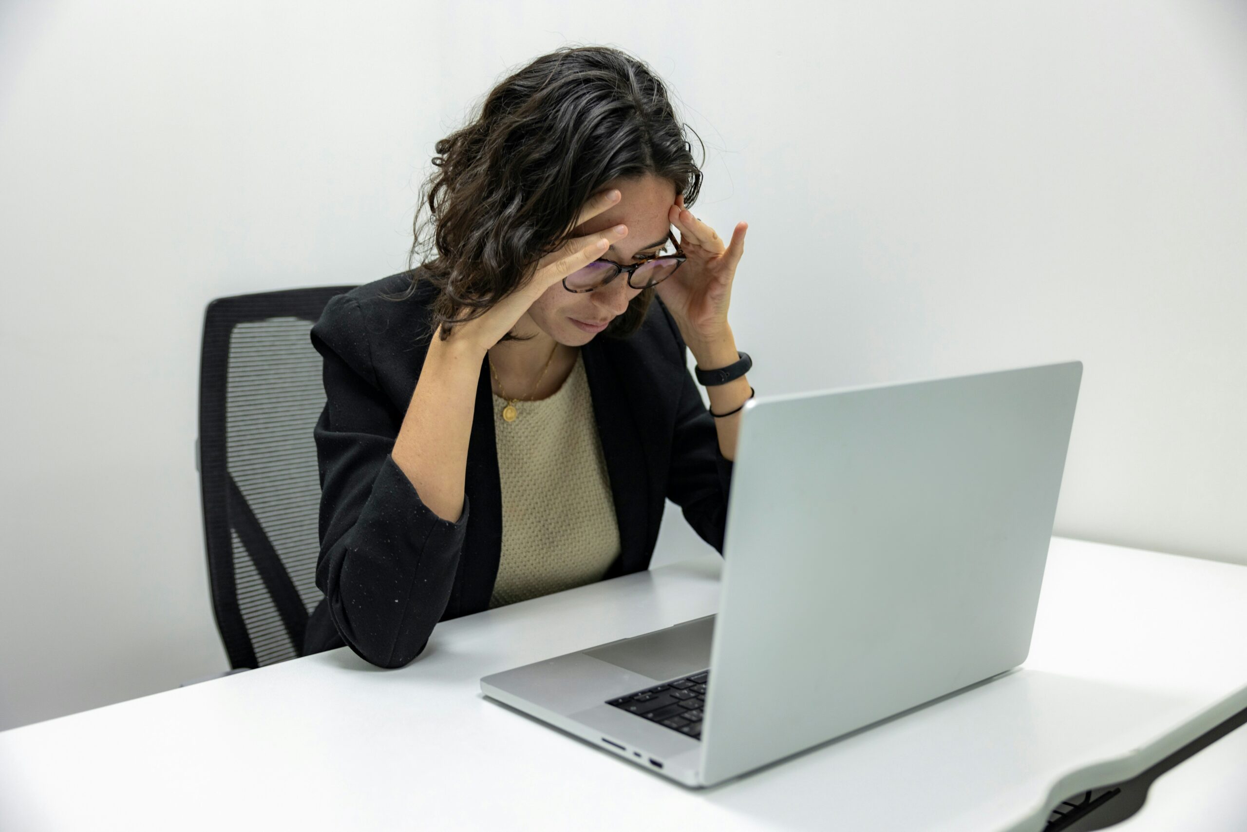 A stressed young woman sitting at a desk with her hands on her head, surrounded by papers and a laptop, representing how chronic stress weakens the immune system.
